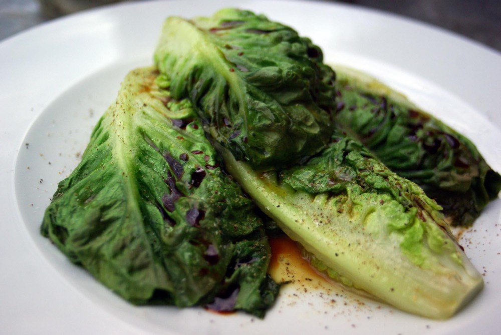 Kalbfleischragout, Kräuter-Gnocchi und Salatherzen ist das Rezept. Auf einem weißen Teller liegen schön drapiert vier halbierte Salatherzen von dunkelgründer Farbe, die vorher angebraten wurden. Etwas Salatsoße bildet einen Spiegel.