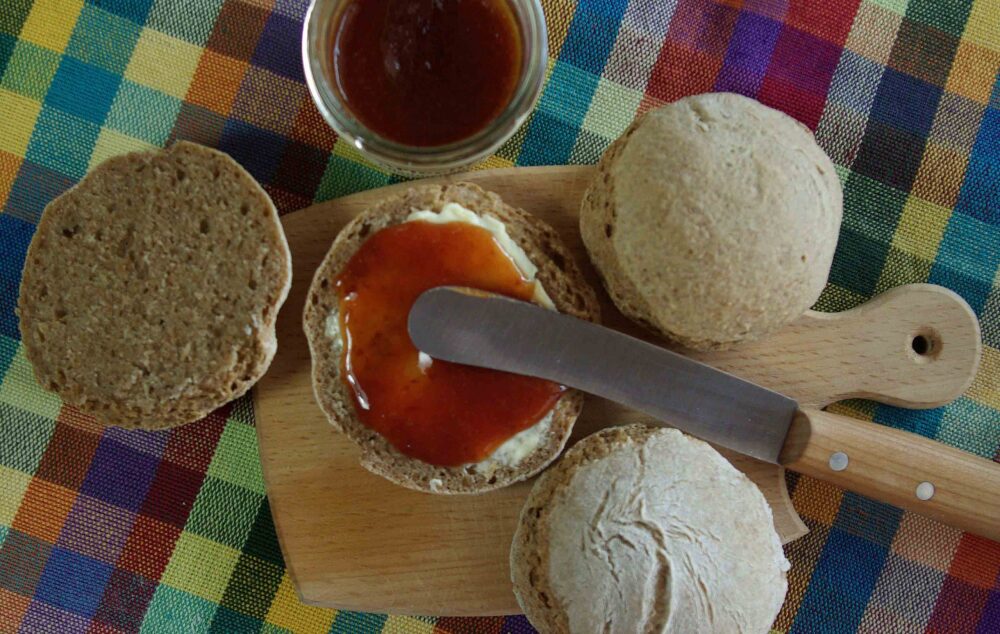 Sonntagsbrötchen zum Wohlfühlen. Frisches Brötchen aufgeschnitten, bestrichen mit Butter und Konfitüre.