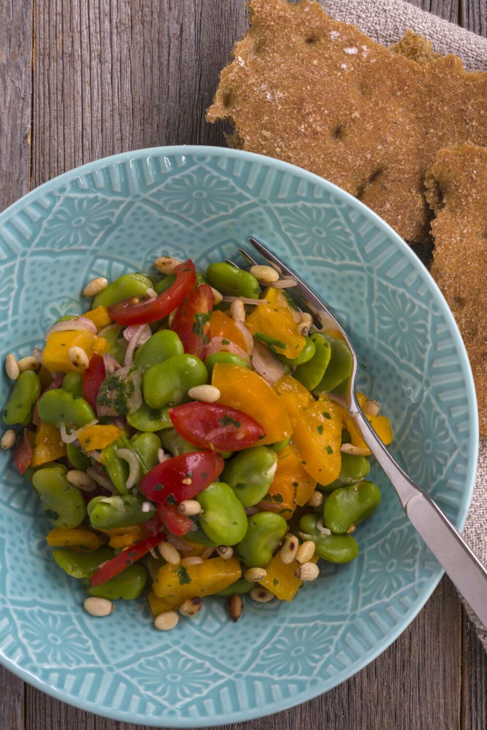 Salat aus dicken grünen Bohnen angerichtet mit Tomaten, Schalotten und Pinienkernen