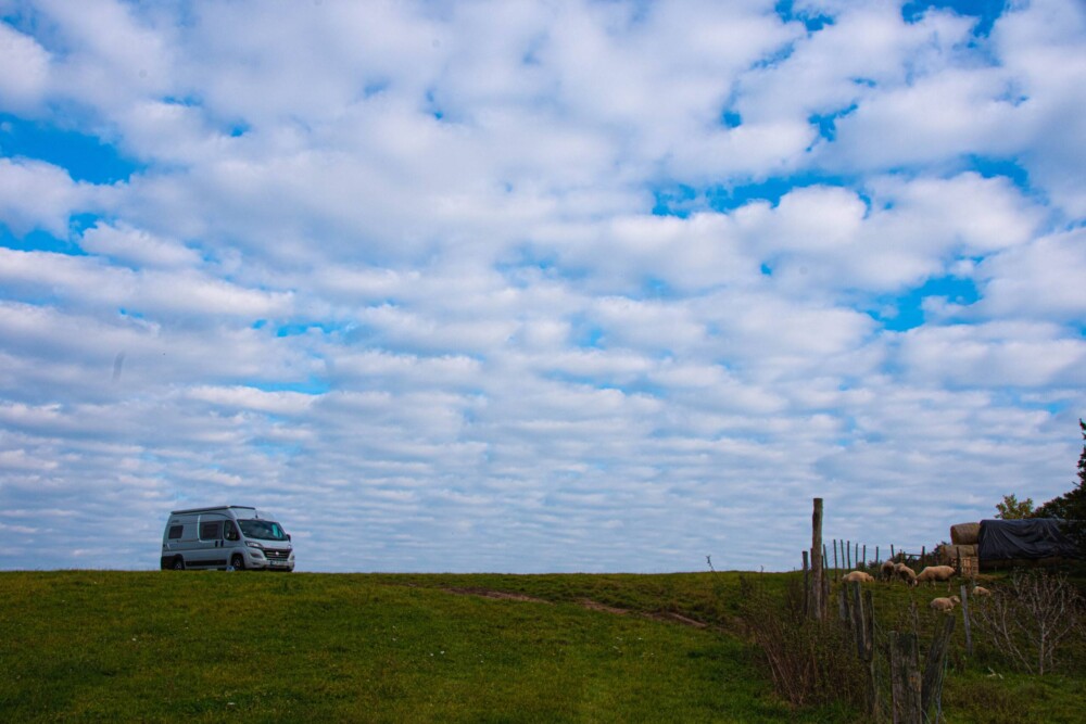 Steigerwald – wir kommen! Ein grauer Campervan steht auf einem Wiesenhügel.