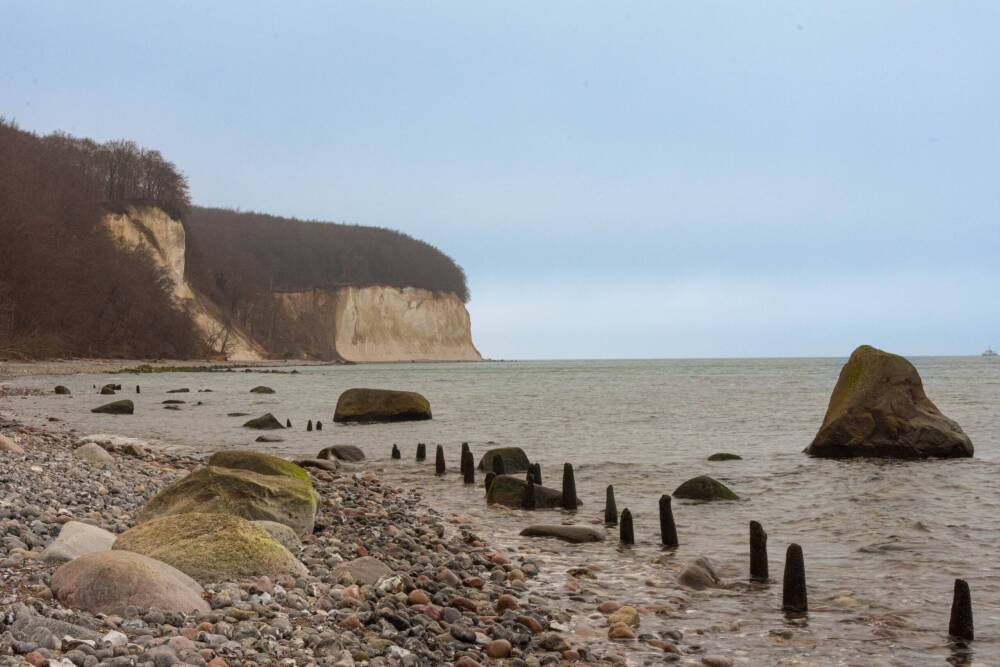 Auf der Insel Rügen am Strand. Langer Kiesstrand mit Blick rechts aufs Meer, links auf die berühmten, fast weißen Kreidefelsen mit grün bewachsener Kuppe.