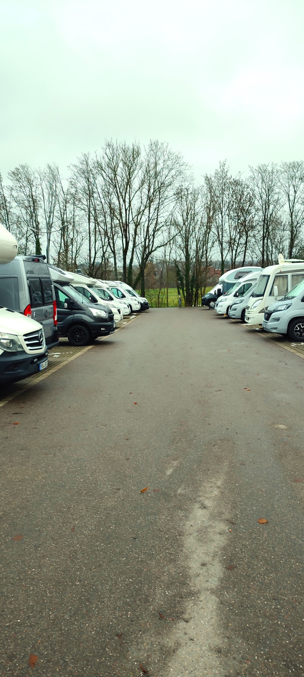 Rudelcamping. Ein Stellplatz, auf dem Wohnmobil an Wohnmobil in einer Reihe steht.