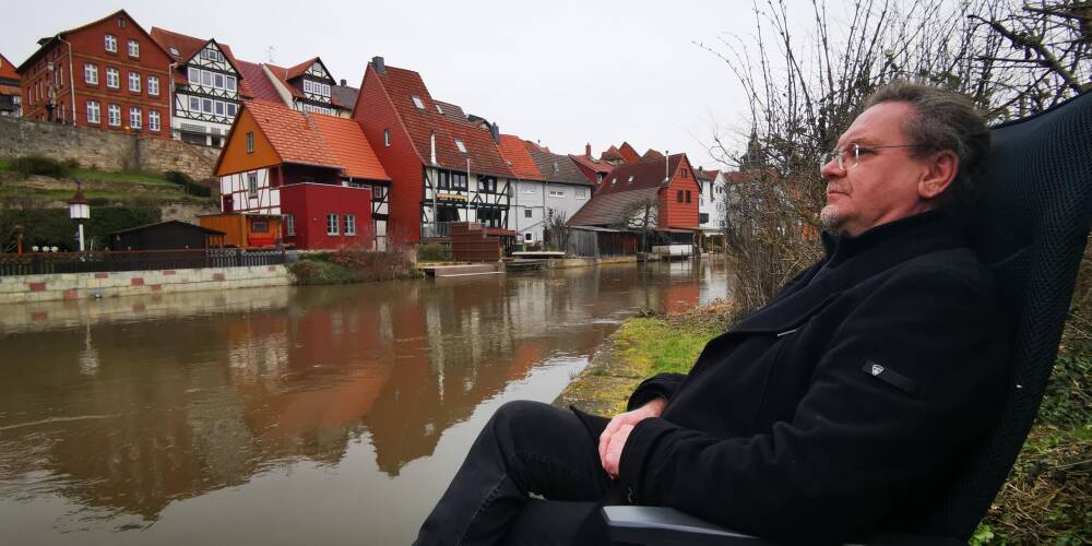 Bad Sooden-Allendorf. Thomas sitzt auf einer Bank an der Werra mit Blick auf die Altstadt