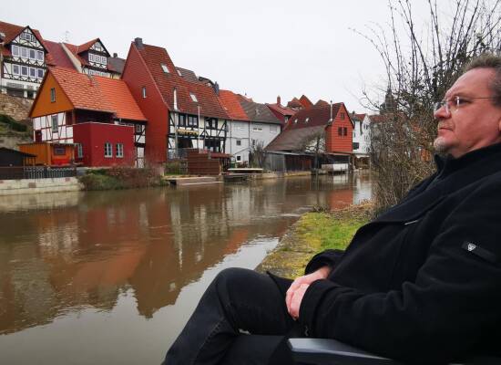 Bad Sooden-Allendorf. Thomas sitzt auf einer Bank an der Werra mit Blick auf die Altstadt